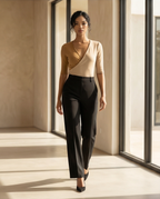 Woman wearing a beige top and black pants in a modern interior setting