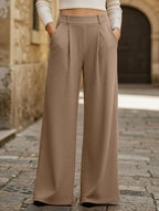 Person wearing beige wide-leg pants standing on a stone pavement.